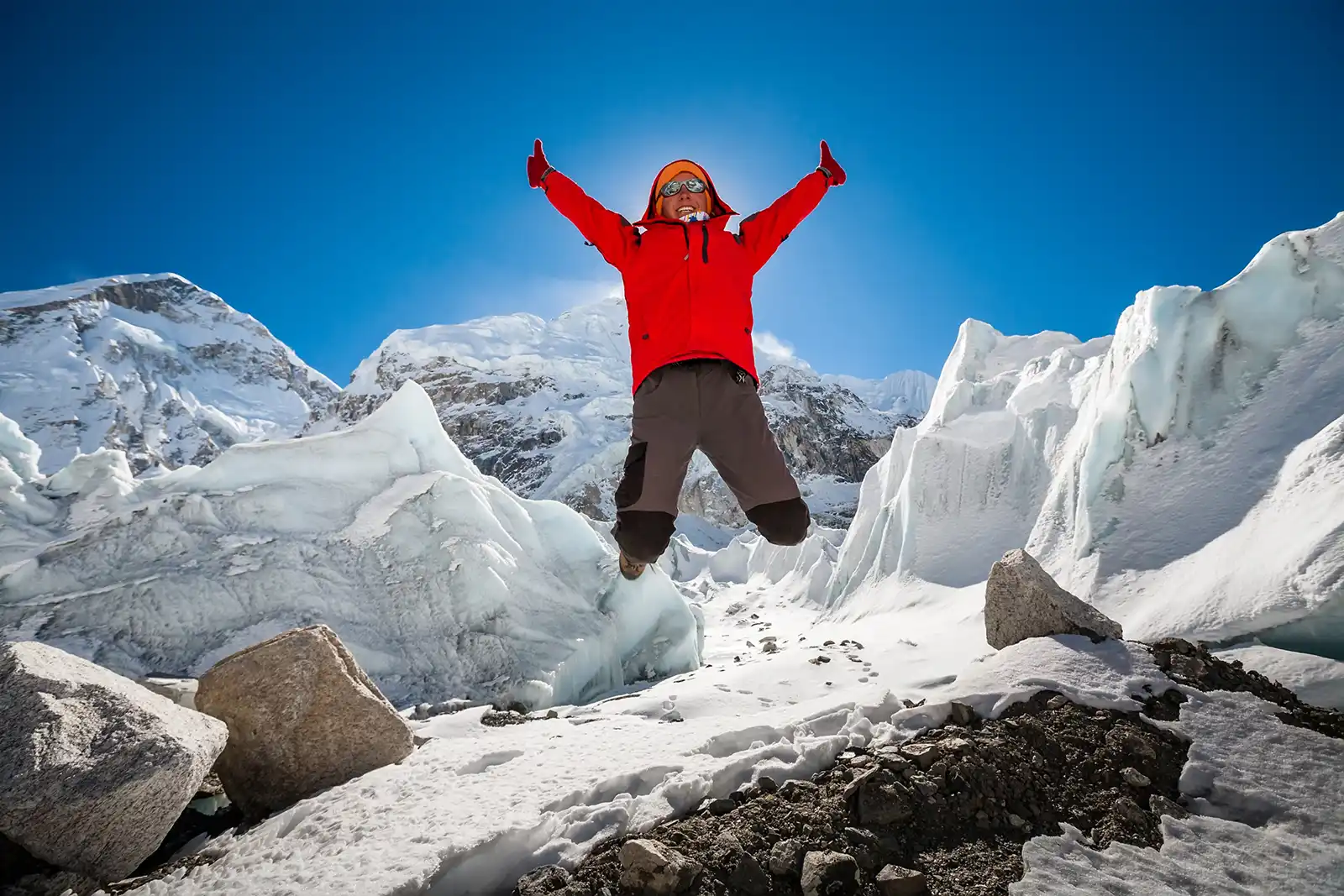 Trekkes is posing at camera in front of huge glacier falling from Everest close to Everest base camp