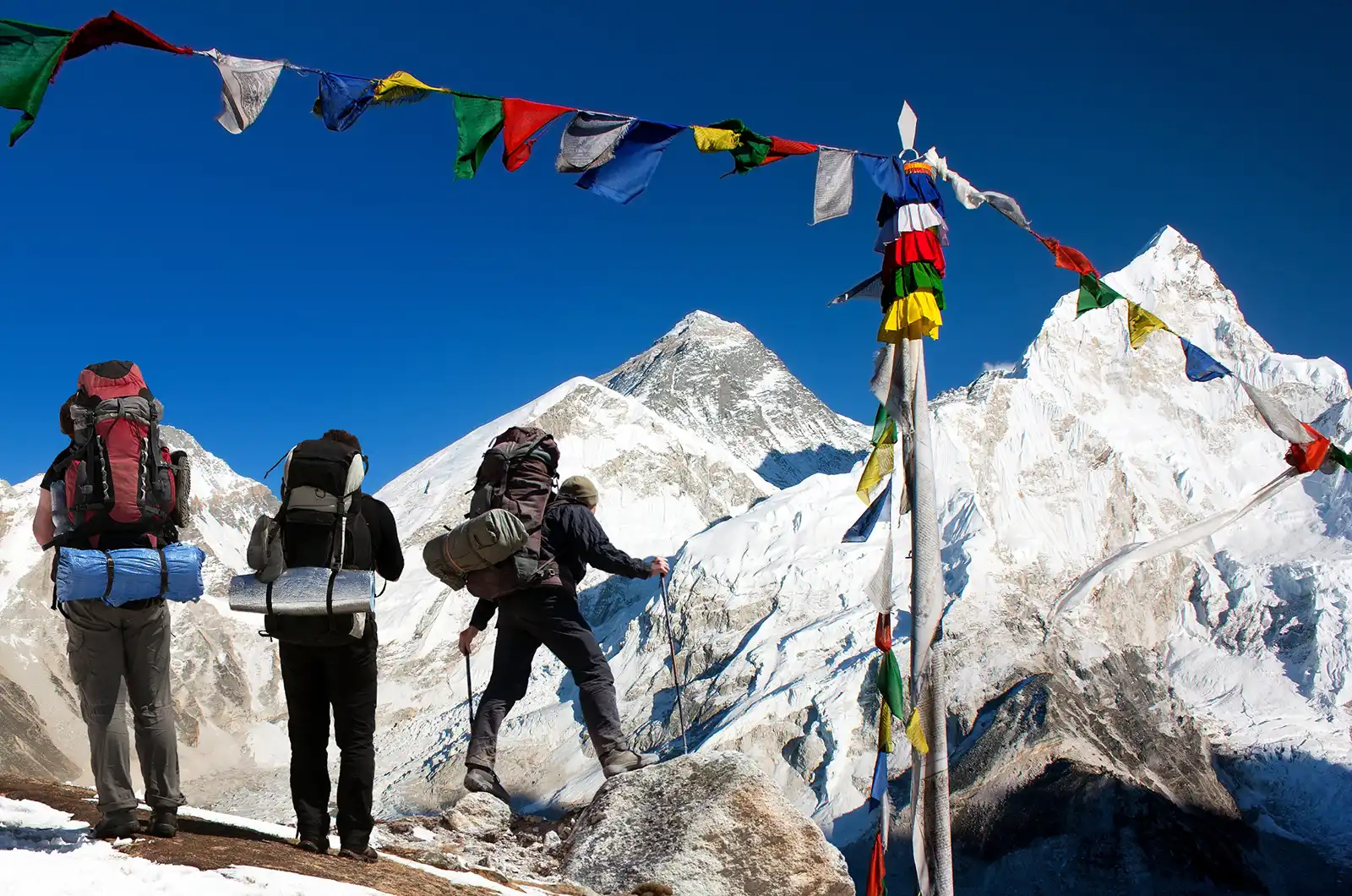 View of Mount Everest with tourists and buddhist prayer flags from Kala Patthar and blue sky