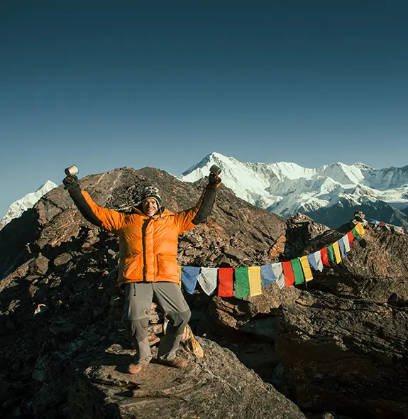 Trekkers relaxing on outdoor chairs while enjoying panoramic views of the Himalayas under clear blue skies.
