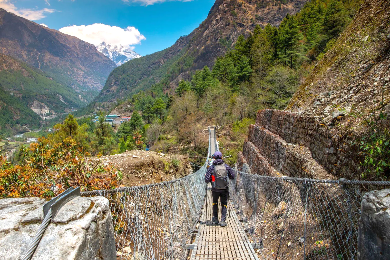 Backpacker crossing suspension bridge on trekking route during Lukla to Phakding