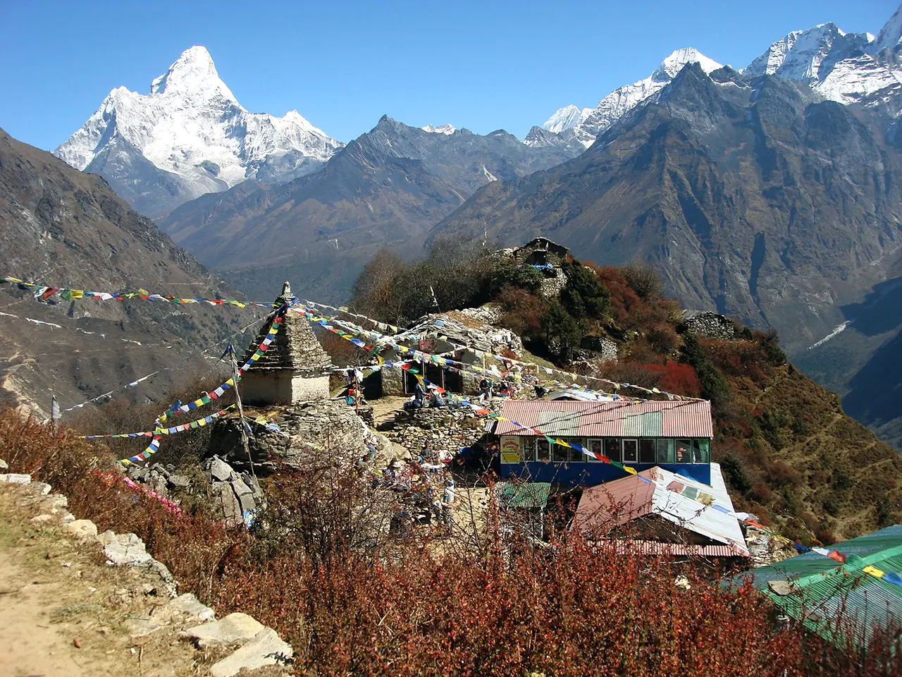 Quang cảnh Ama Dablam nhìn từ Mongla Danda với những lá cờ cầu nguyện, một bảo tháp nhỏ và quán trà dọc theo đường mòn leo núi Everest.