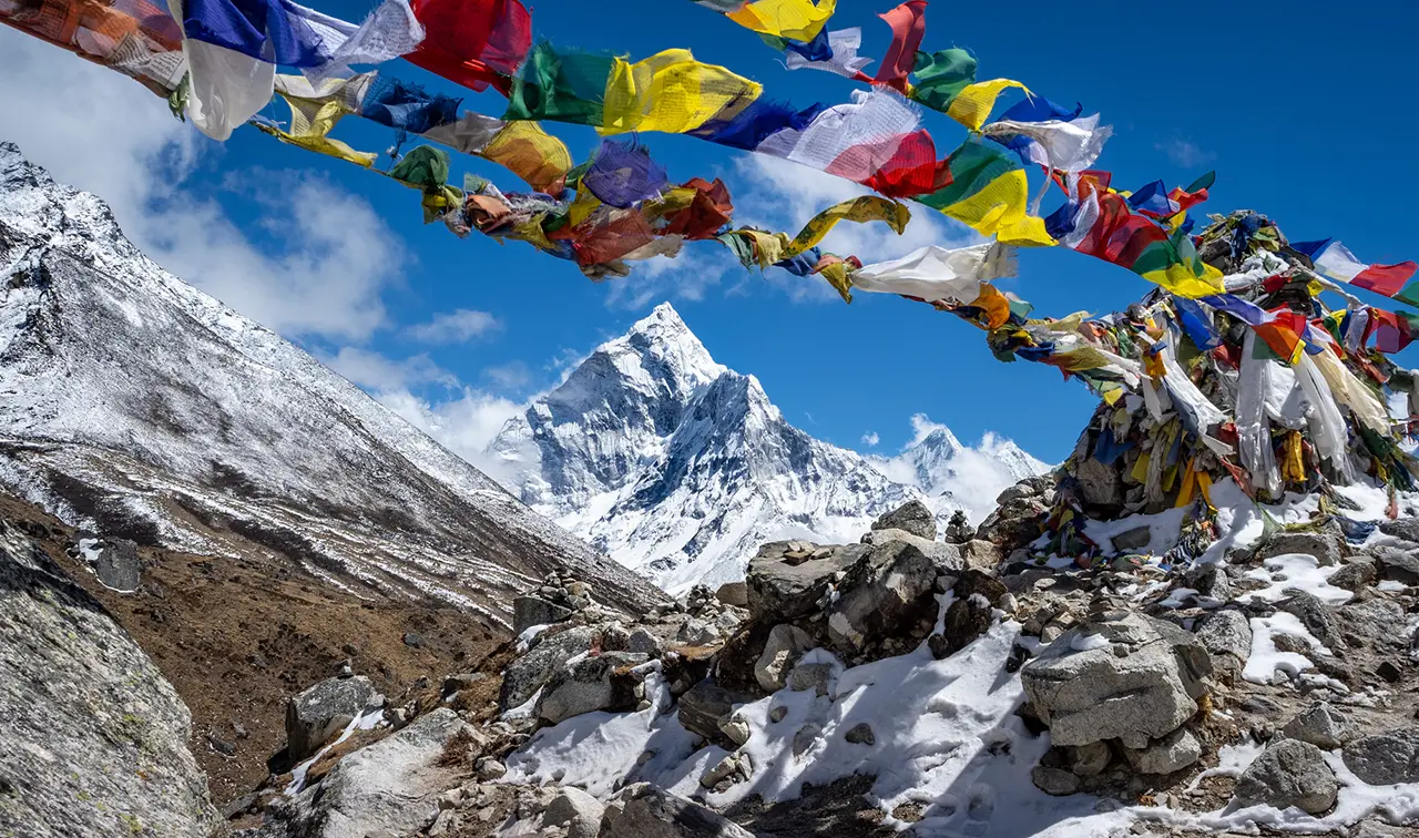 Colorful prayer flags at Thukla Pass with Ama Dablam rising in the background along the Everest Base Camp trekking route.