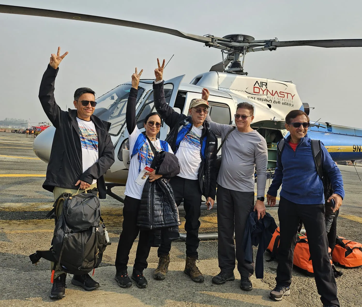 a group of people posing for a photo in front of a helicopter