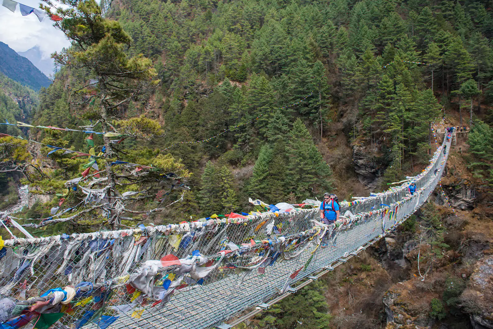 trekker cross the river by suspension bridge