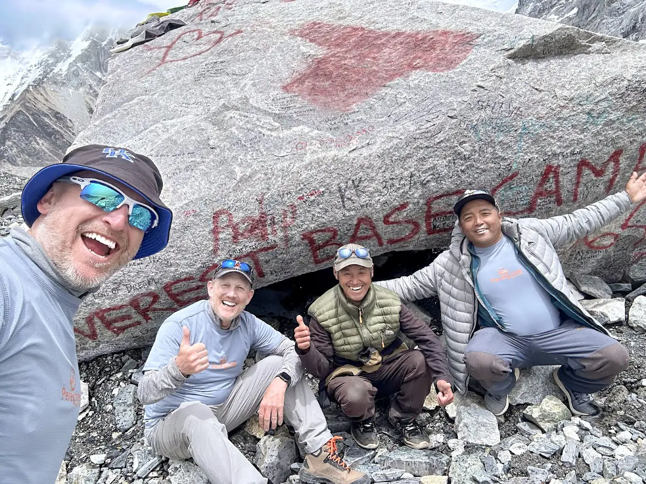 Peregrine clients and guides celebrating at the Everest Base Camp rock marker at 5,364 m