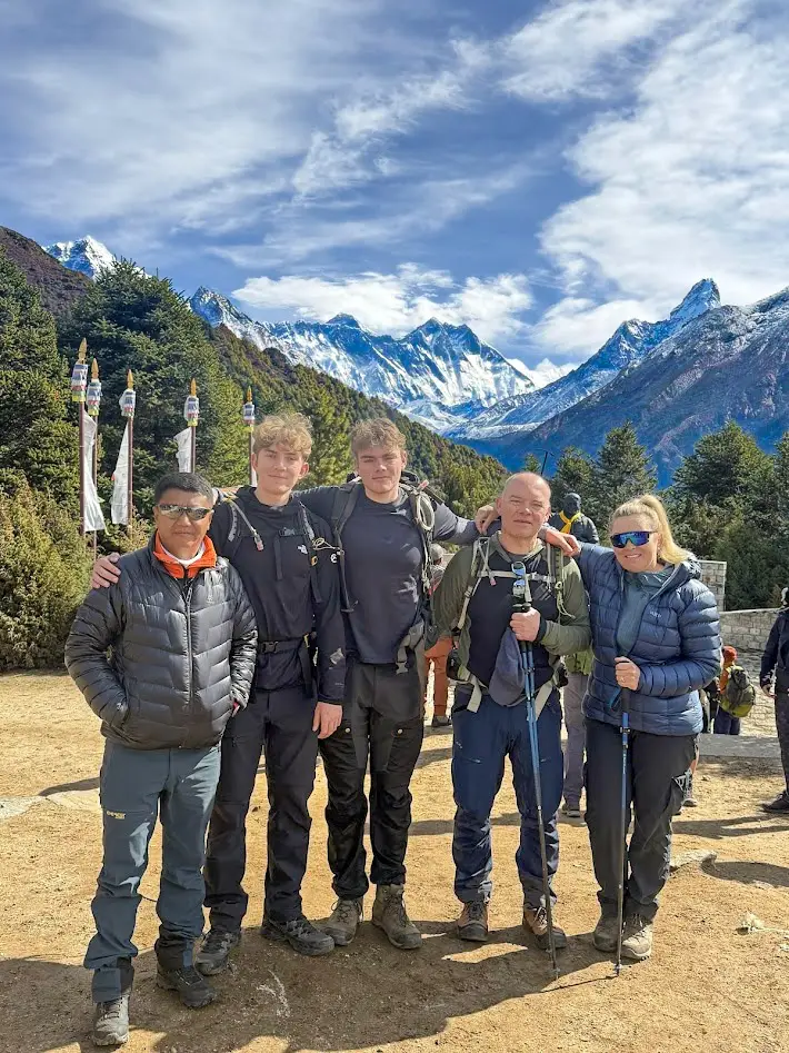 Peregrine guide with a family of trekkers at Tengboche with Everest, Lhotse, and Ama Dablam in the background on the luxury Everest Base Camp trek