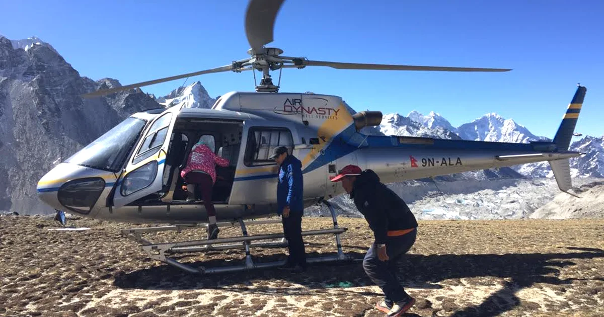 An Air Dynasty helicopter landed at the Kala Patthar viewpoint with snow-capped Himalayan mountains and the Khumbu Glacier in the background, as passengers board for an Everest base camp helicopter return tour.