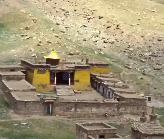 Aerial view of a remote Tibetan monastery along the Inner Kora of Mount Kailash, surrounded by sparse, rocky terrain.