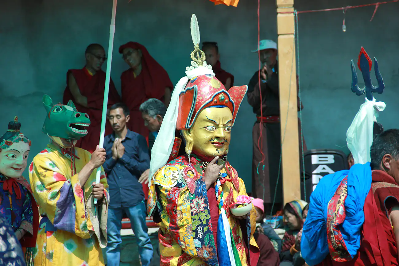 Performers in traditional masks and vibrant costumes portraying the Eight Manifestations of Guru Rinpoche at Takthok Monastery, Ladakh, India.