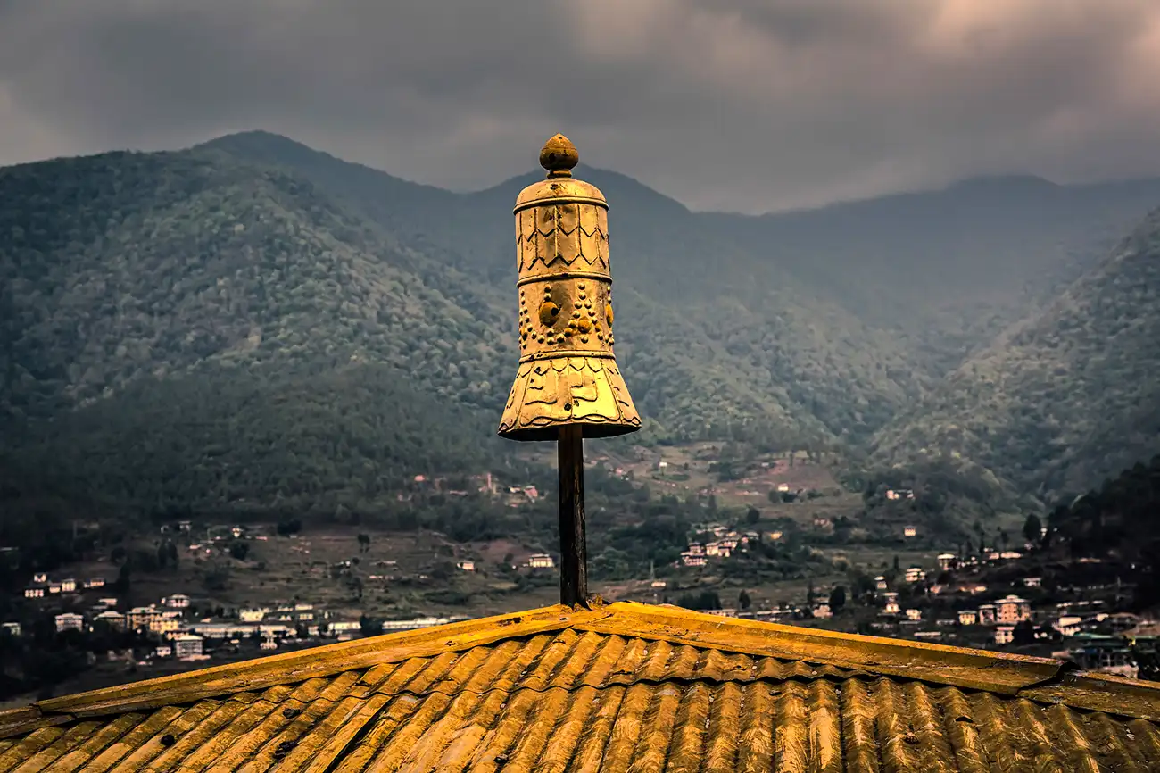 Golden spire atop Chimi Lhakhang monastery with mountains in the background