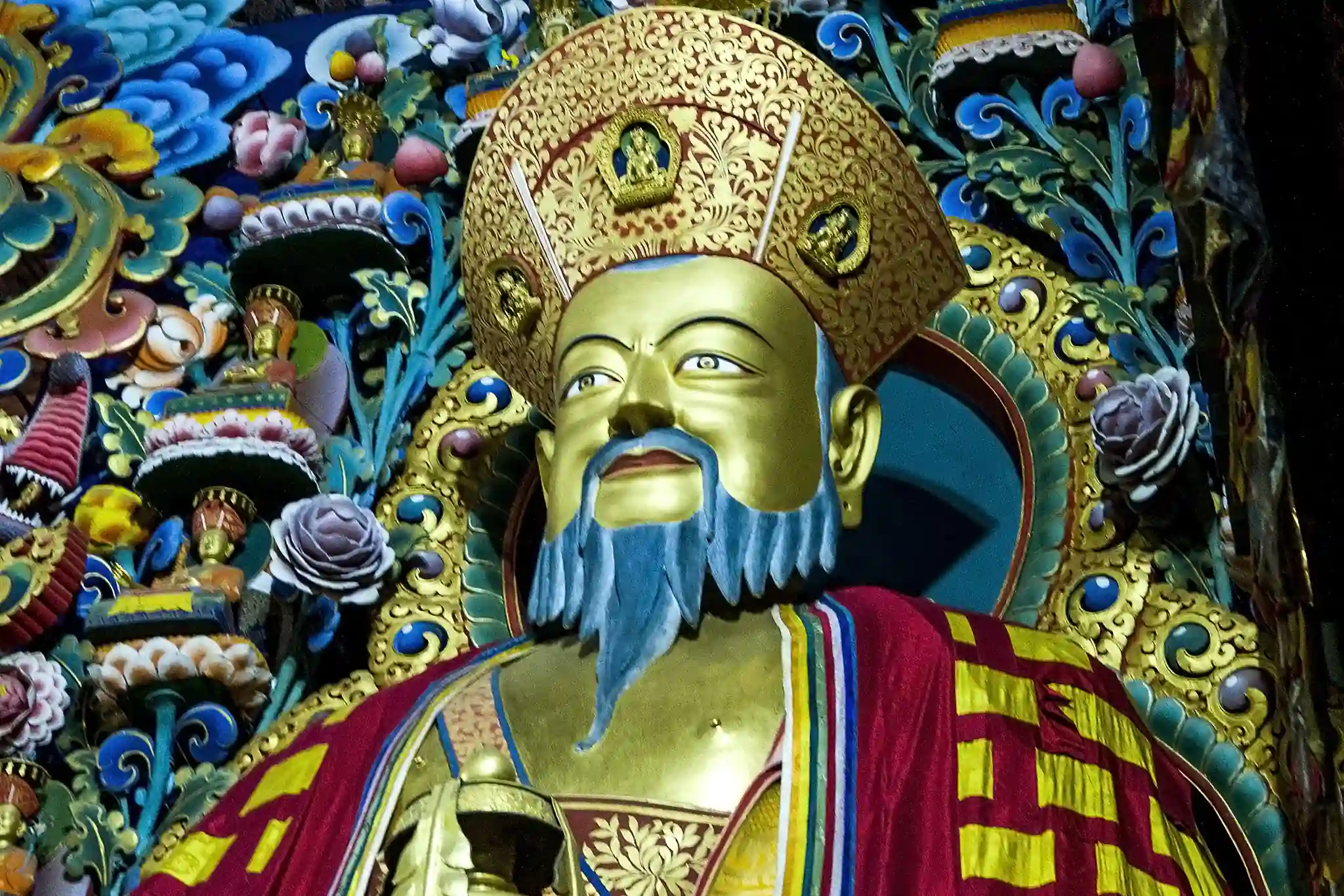 Statue of Zhabdrung Ngawang Namgyal, adorned in traditional Bhutanese robes and an elaborate headdress, surrounded by intricate decorations.