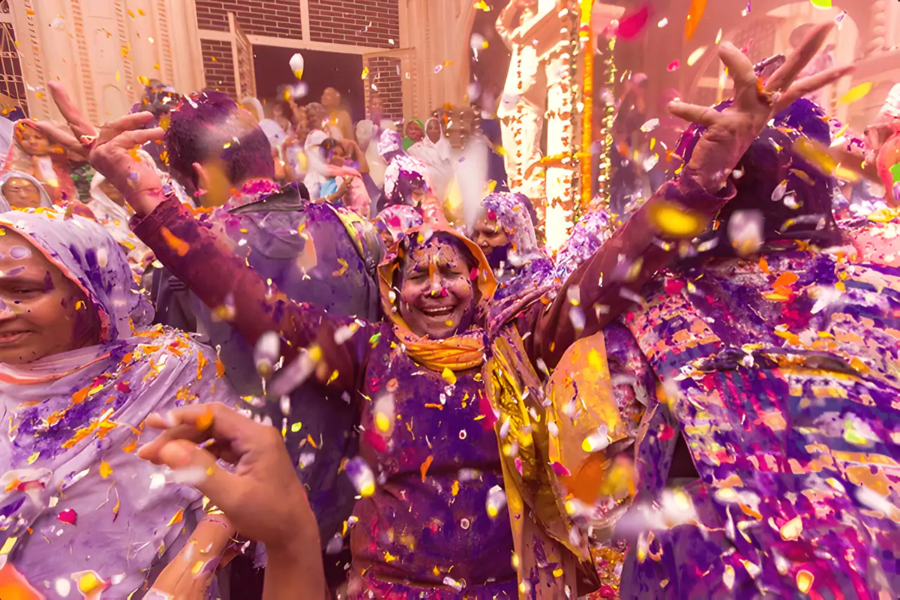 Indian widow joyfully celebrating Holi with vibrant colors at Gopinath Temple in Vrindavan, Uttar Pradesh.