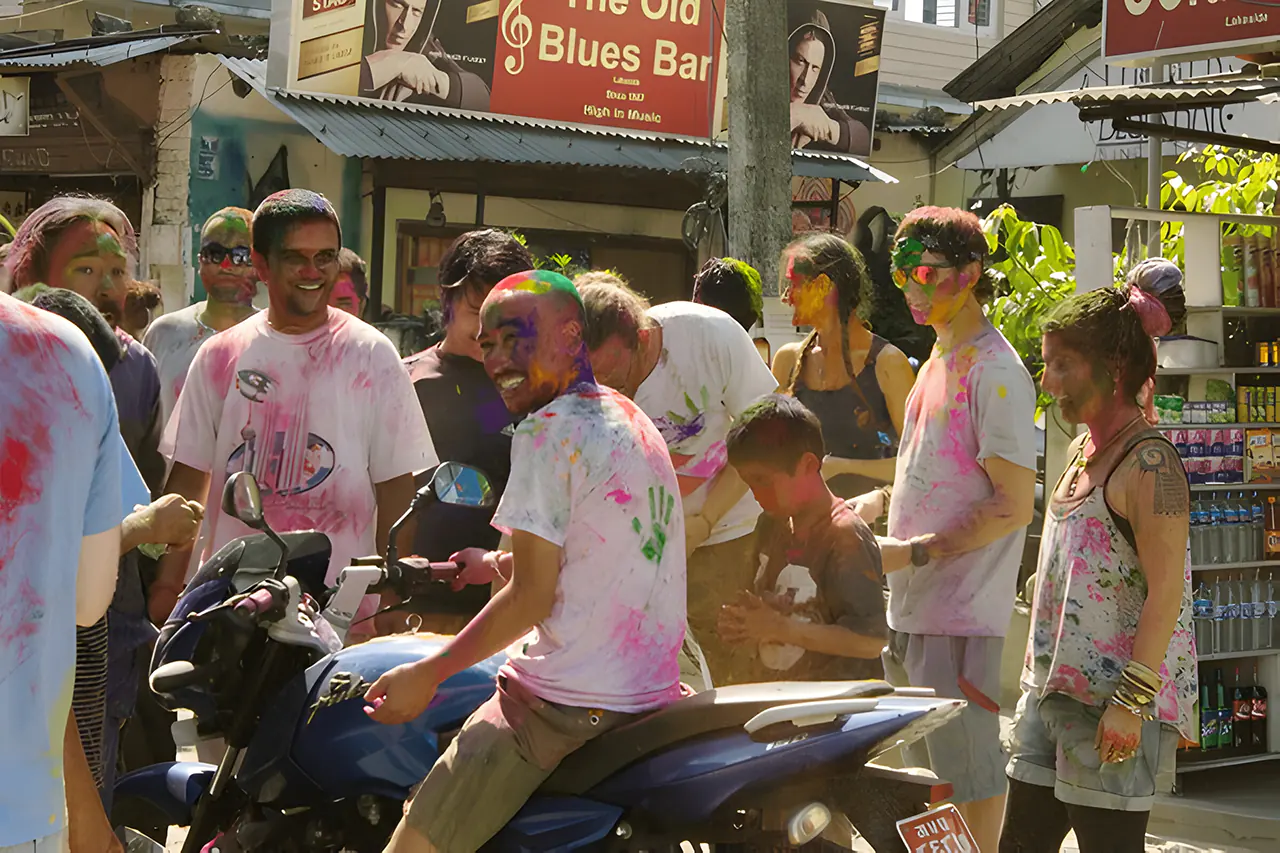 Diverse group of people celebrating Holi festival with colorful powders in the streets of Pokhara, Nepal.