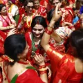 Nepalese Hindu women in vibrant red sarees dancing and celebrating during the Haritalika Teej festival at Pashupatinath Temple in Kathmandu.