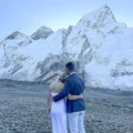 A newly married couple standing together, embracing and looking out at the snowy peaks of Kala Patthar in the Himalayas.