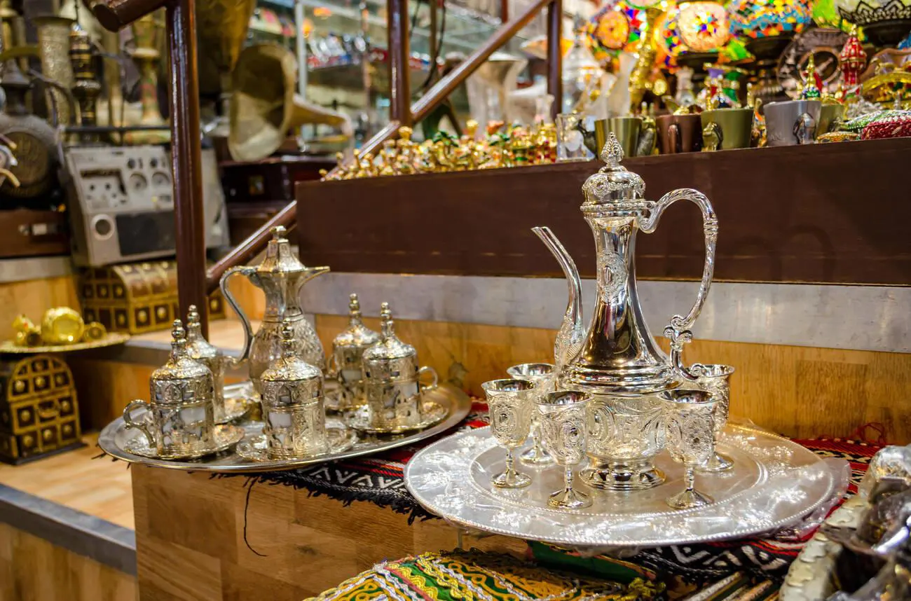 Exquisite Omani coffee sets on display, featuring intricately designed silver cups and jugs in a Muscat shop.