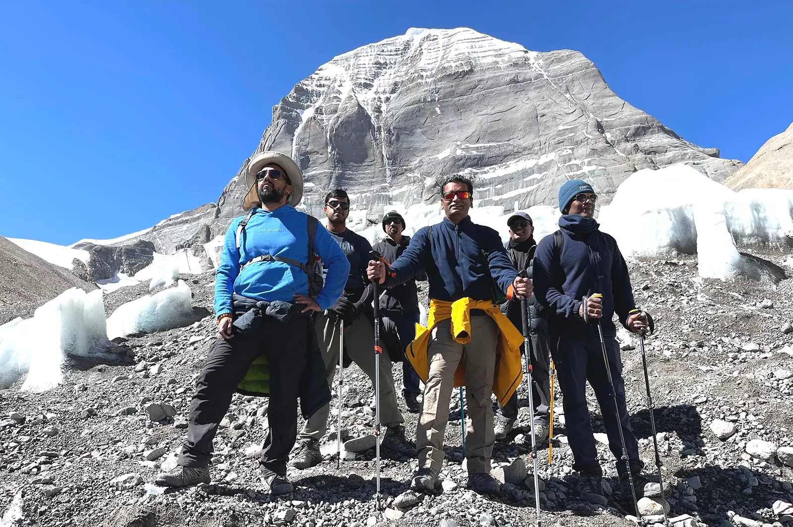 Group of trekkers standing in front of Mount Kailash with trekking gear.