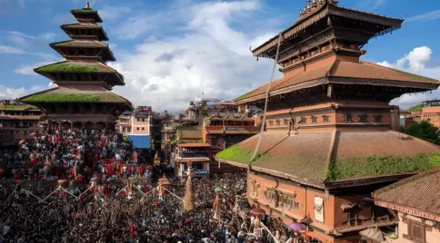Throngs of Nepalese devotees participate in a Gai Jatra procession carrying a straw effigy through Bhaktapur's historical square.