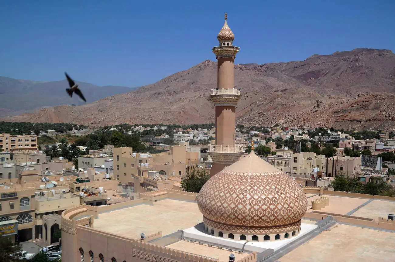 Nizwa Mosque viewed from Nizwa Fort with mountains in the background, Oman