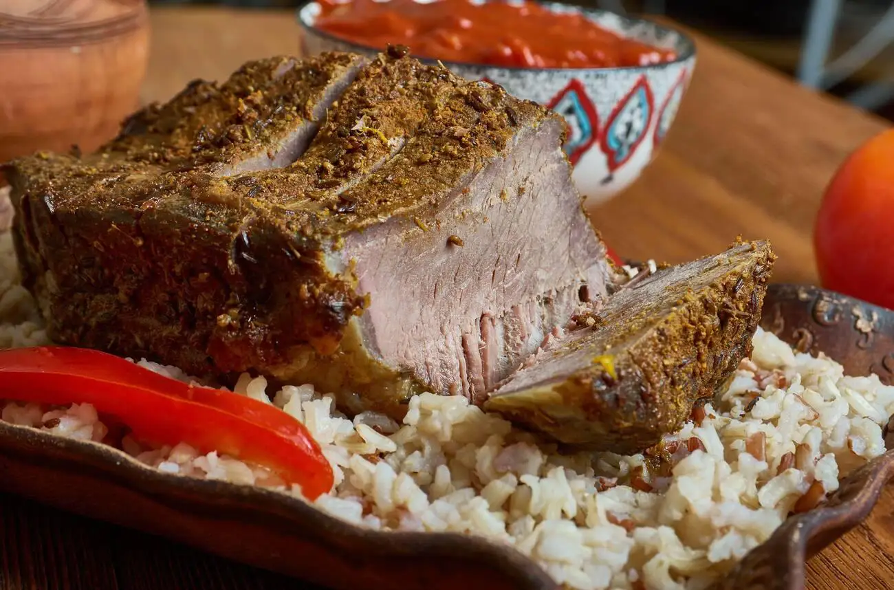 Shuwa, a traditional Omani dish, featuring slow-cooked bone-in lamb served over rice with spices.