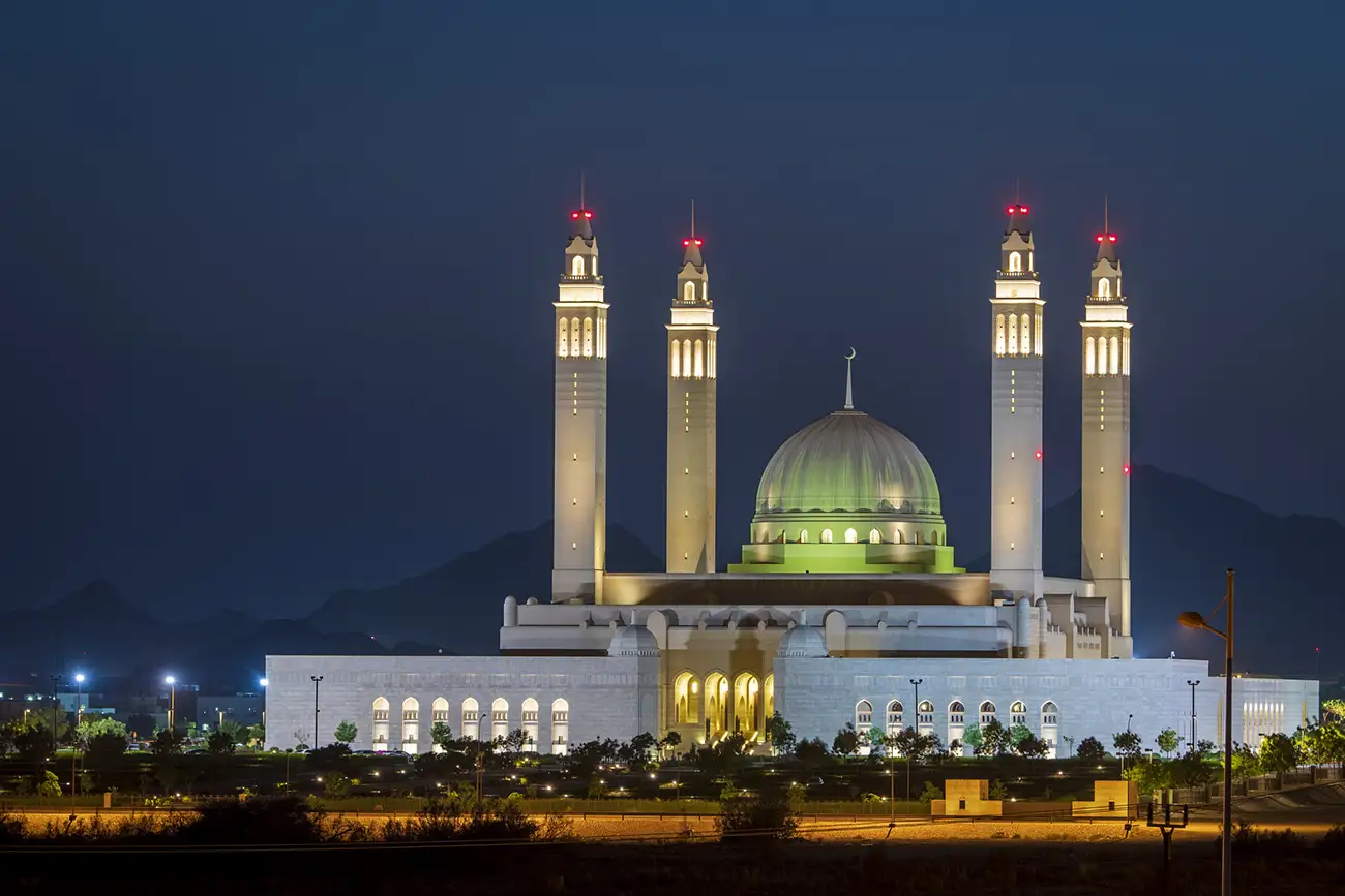 Sultan Qaboos Mosque in Nizwa, Oman, illuminated at night with its grand dome and minarets.
