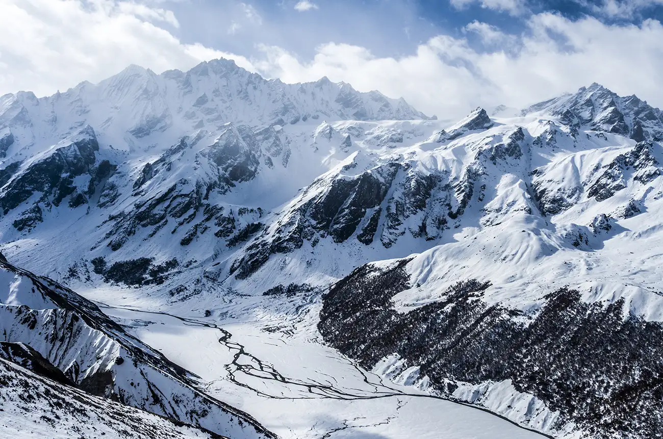 Snow-covered mountains and a frozen river valley as seen from the top of Kyangjin Ri in Nepal.