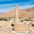 Panoramic view of Nizwa Mosque and the Nizwa City, Oman, from Nizwa Fort with mountains in the background.