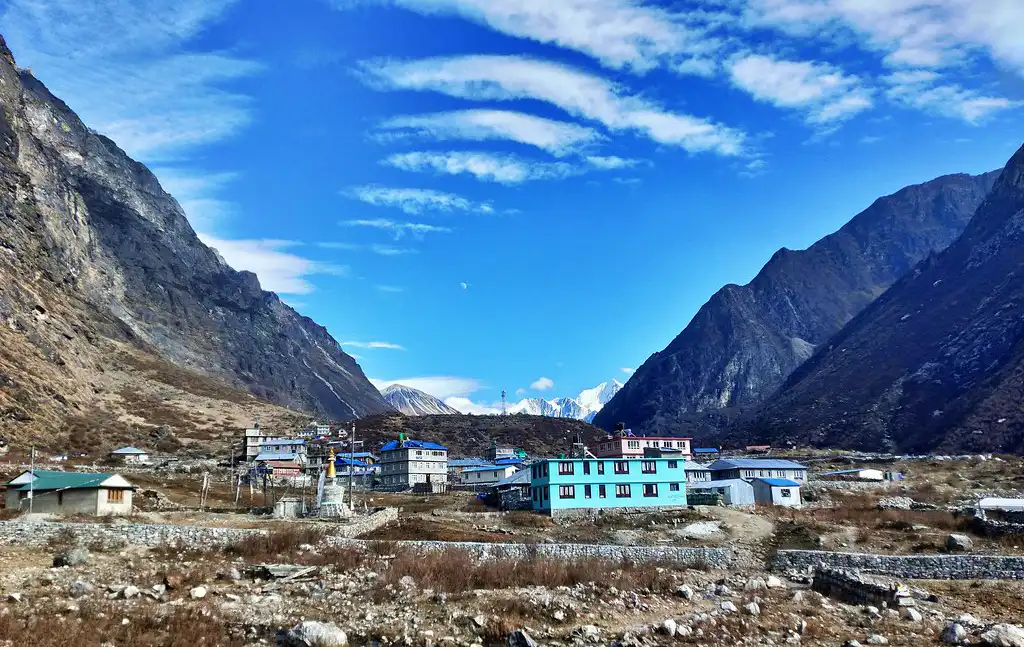 Picturesque Langtang Village nestled between towering mountains under a bright blue sky.