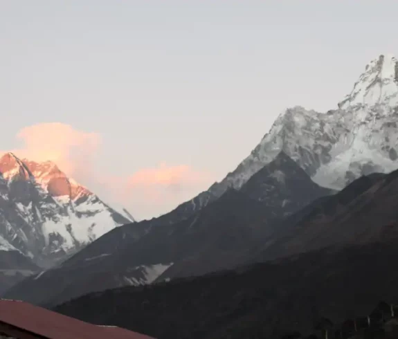 Panoramic view of snow-capped mountains from Chhukung Village at sunrise, with prayer flags in the foreground.