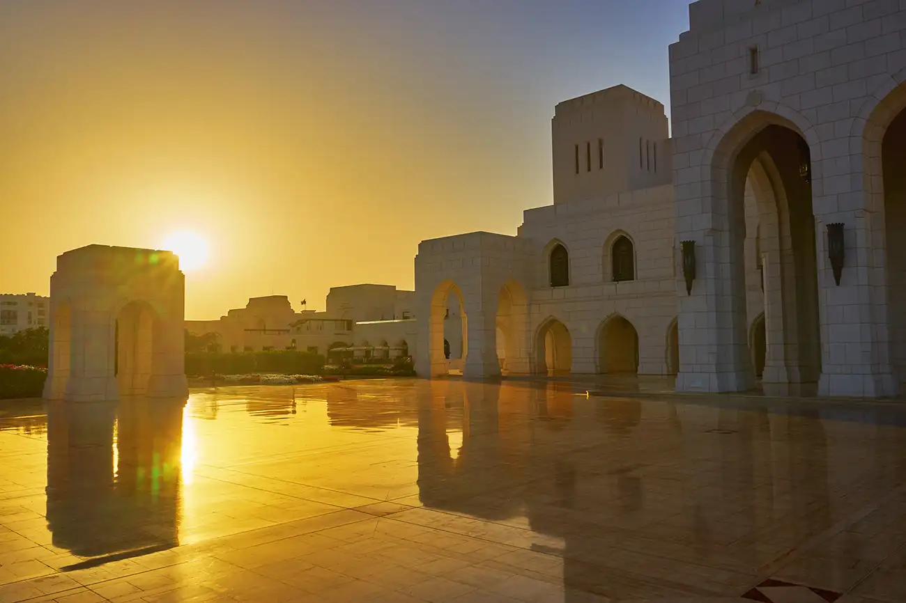 The Royal Opera House in Muscat, Oman, bathed in the warm, golden light of a sunset, casting reflections on the polished floor.