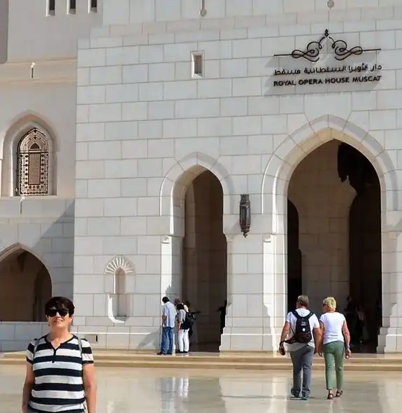 Visitors outside the grand entrance of the Royal Opera House Muscat, featuring its iconic arched doorways and elegant white stone facade.