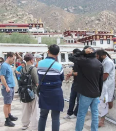 Tourists exploring Drepung Monastery in Lhasa, Tibet, with the monastery buildings in the background.