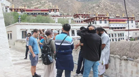 Tourists exploring Drepung Monastery in Lhasa, Tibet, with the monastery buildings in the background.