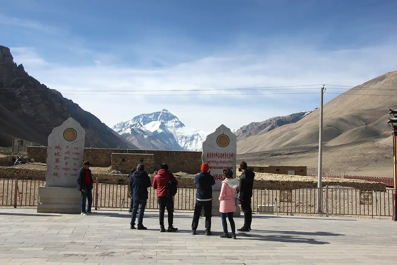 Tourists visiting the North Everest Base Camp monument with Mount Everest in the background.