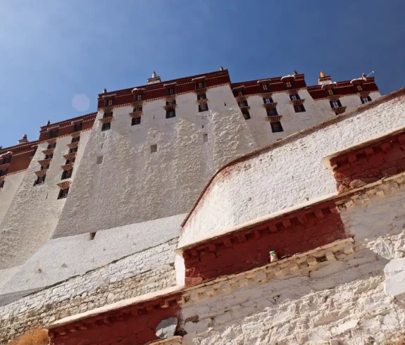 Looking up at the towering Potala Palace in Lhasa, Tibet, with the clear blue sky above.