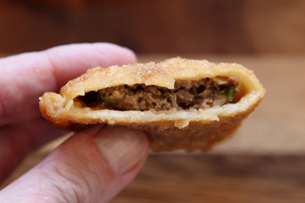 A halved sha phaley showcasing its crispy fried exterior and savory filling of minced meat and spices.