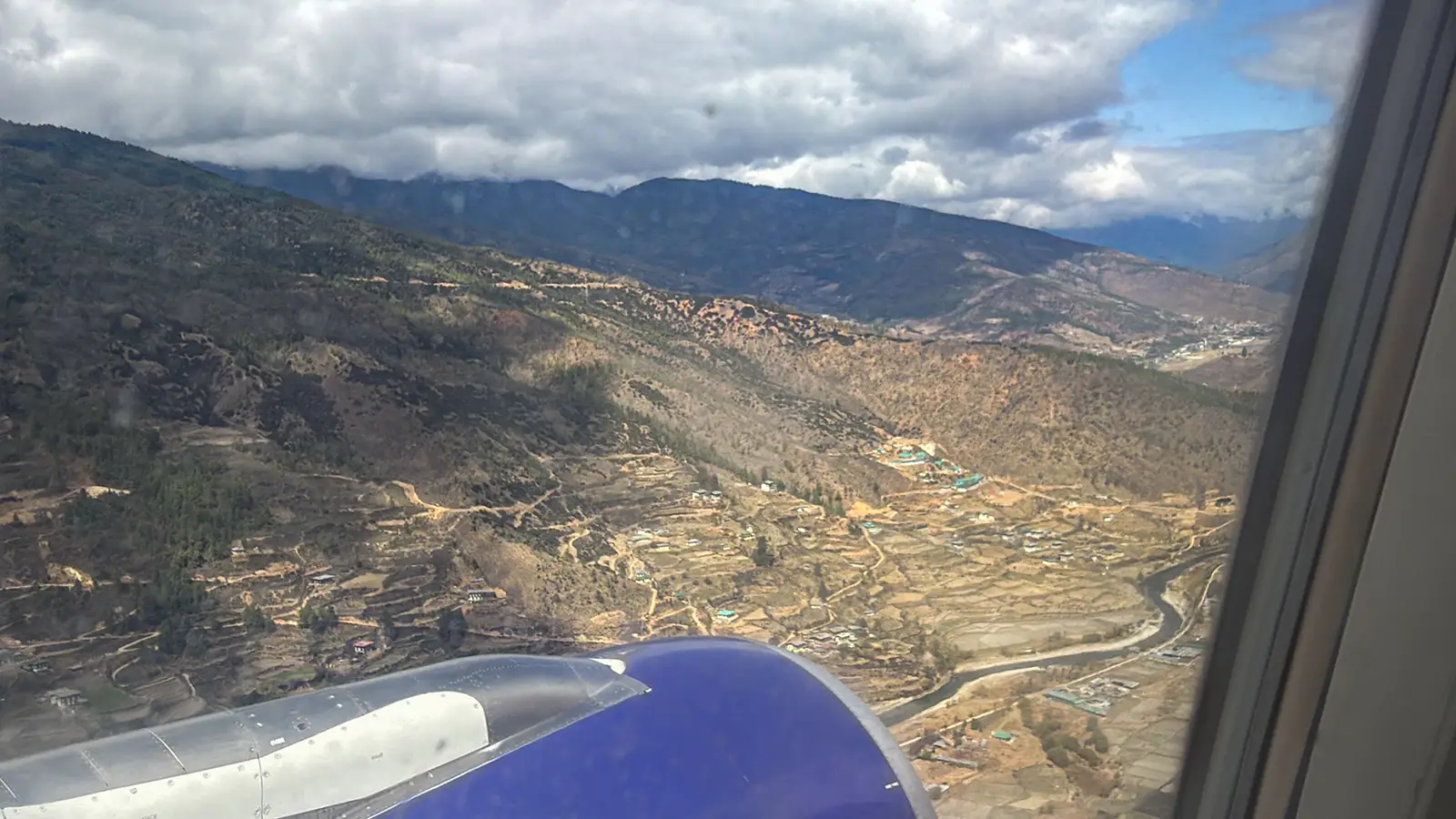 Aerial view of terraced farmland and mountain valley during descent into Paro Bhutan