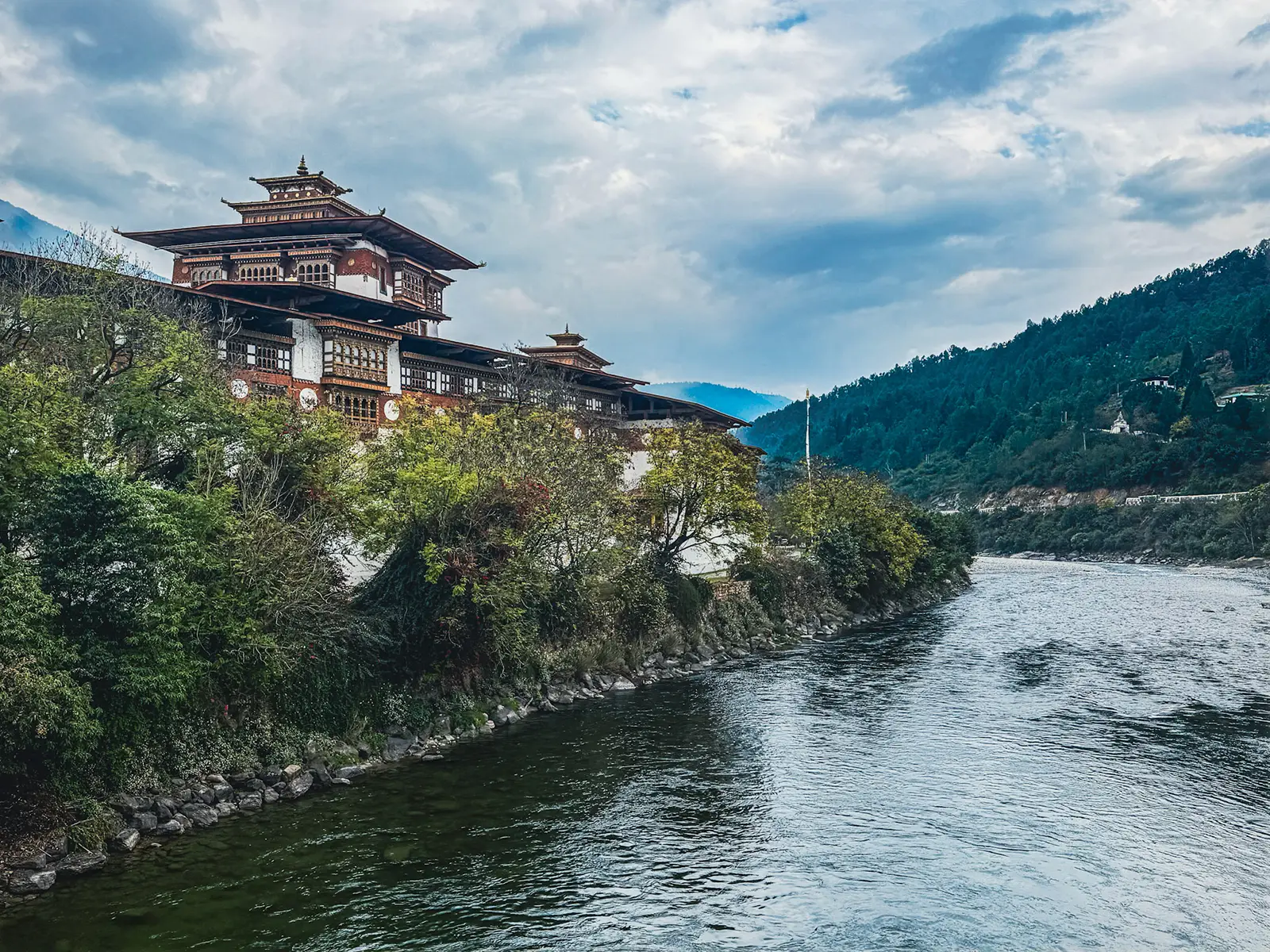 Punakha Dzong riverside view in Bhutan with traditional architecture and forested hills