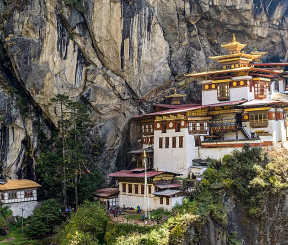 The iconic Tiger's Nest Monastery (Paro Taktsang) with its traditional white and gold architecture, clinging to a steep granite cliff in Bhutan.