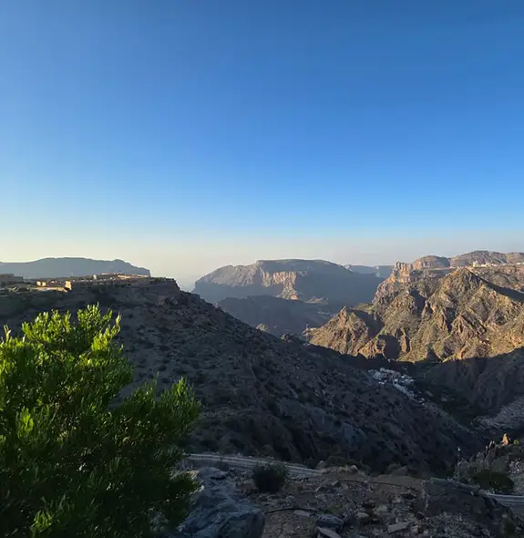 Panoramic mountain landscape of Jabal Akhdar in Oman, showing rugged cliffs, deep valleys, and highland villages.