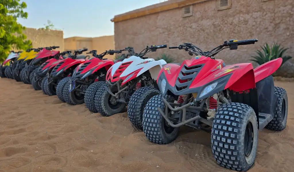 A row of quad bikes parked on desert sand, ready for dune bashing and ATV safari adventure.