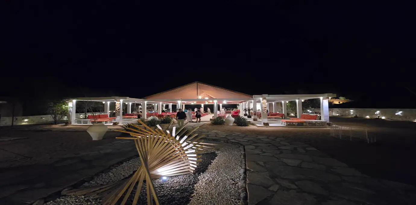 Night view of Sama Al Wasil Desert Camp with illuminated seating areas in Wahiba Sands, Oman.