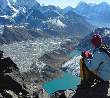 Trekker resting on a rocky viewpoint during the Luxury Gokyo Ri Trek, overlooking turquoise Gokyo Lakes, glaciers, and Himalayan peaks