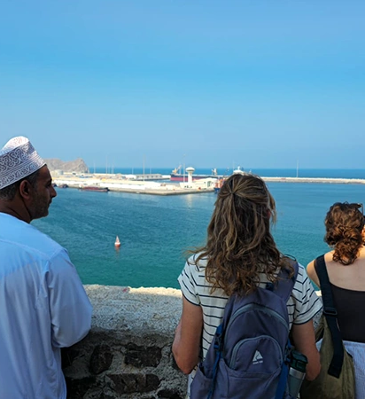 Travelers overlooking Muscat harbor during the Oman Grand Explorer tour, enjoying coastal views and local culture.