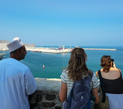 Travelers overlooking Muscat harbor during the Oman Grand Explorer tour, enjoying coastal views and local culture.