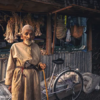 Desa dan Benteng Tradisional Oman - Seorang pria tua Oman berdiri dengan tongkat di samping sepeda dekat kios pasar tradisional.