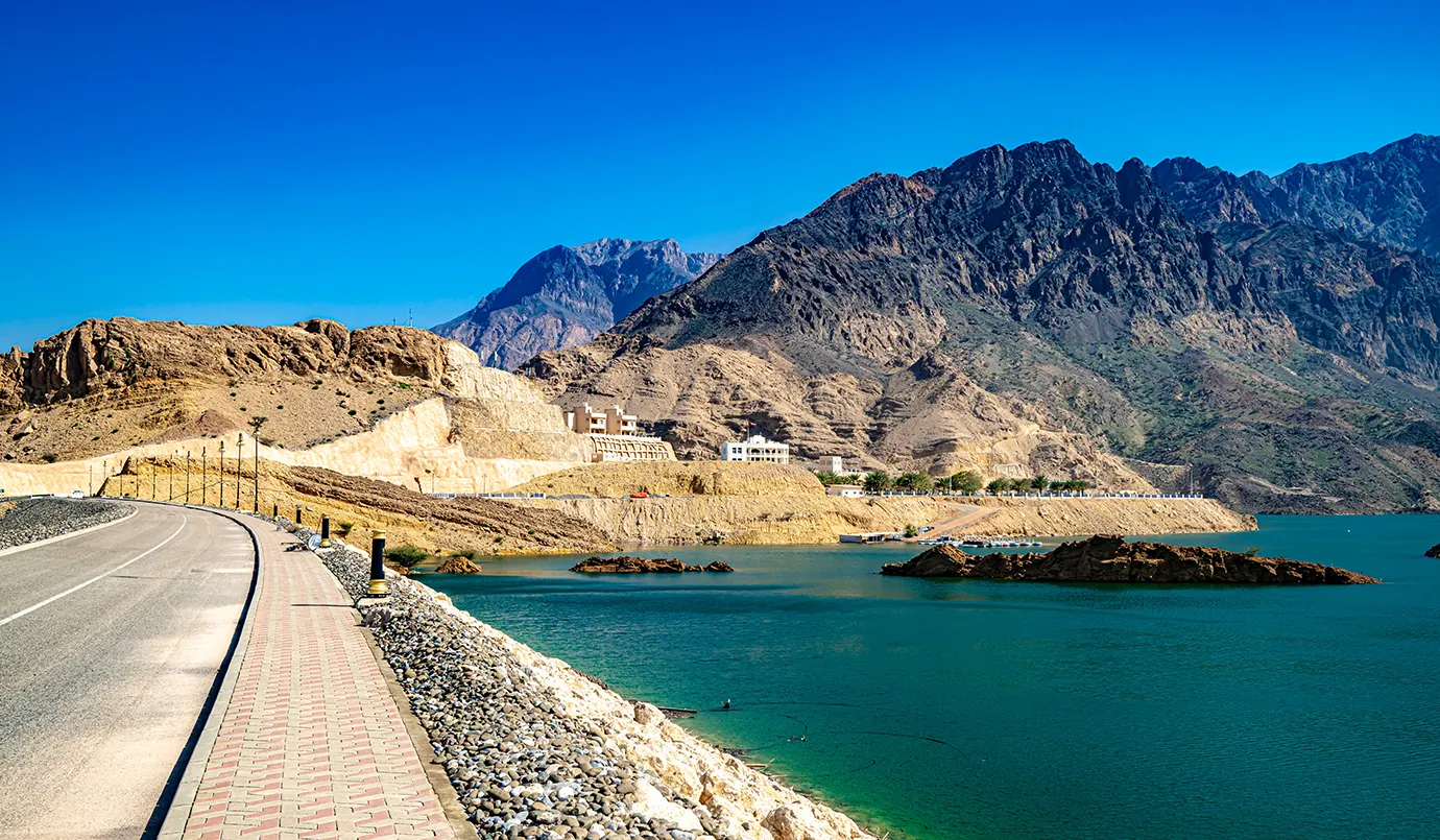 Wadi Dayqah Dam with turquoise water, mountain landscape, and scenic road in Oman.