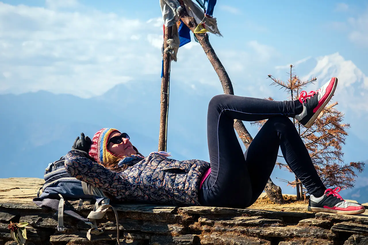 Trekker resting on a stone platform with mountain views during an acclimatization break, showing a practical moment tied to Everest Base Camp altitude sickness prevention.