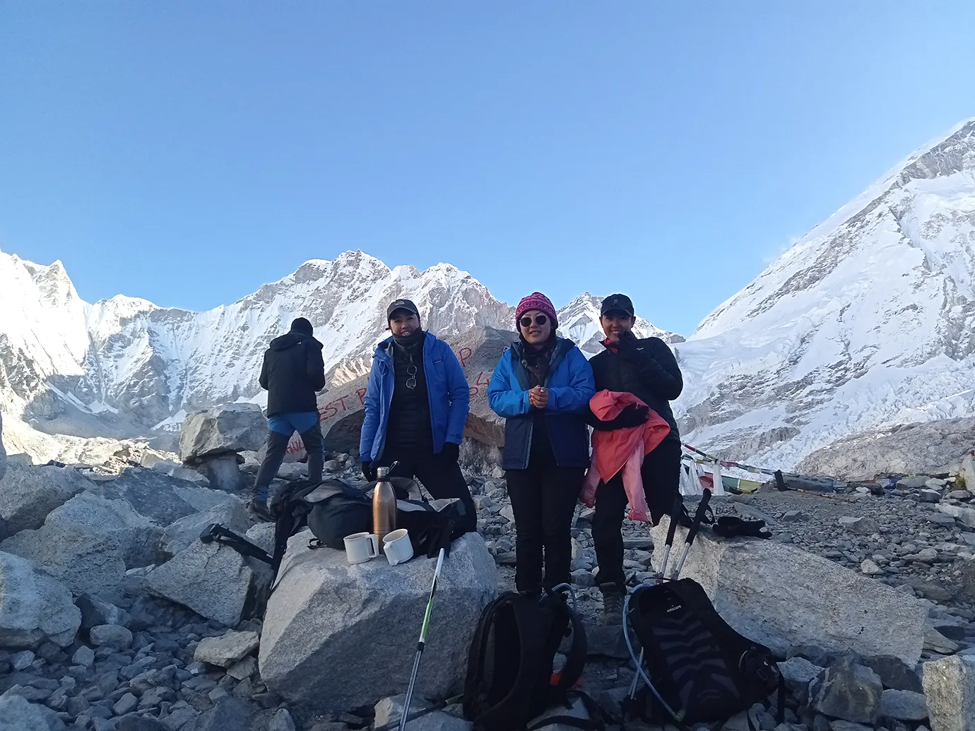 A group of female trekkers posing with their private guide to the Everest Base Camp Trek at the iconic EBC rock marker, surrounded by the towering, snow-covered Himalayan peaks.