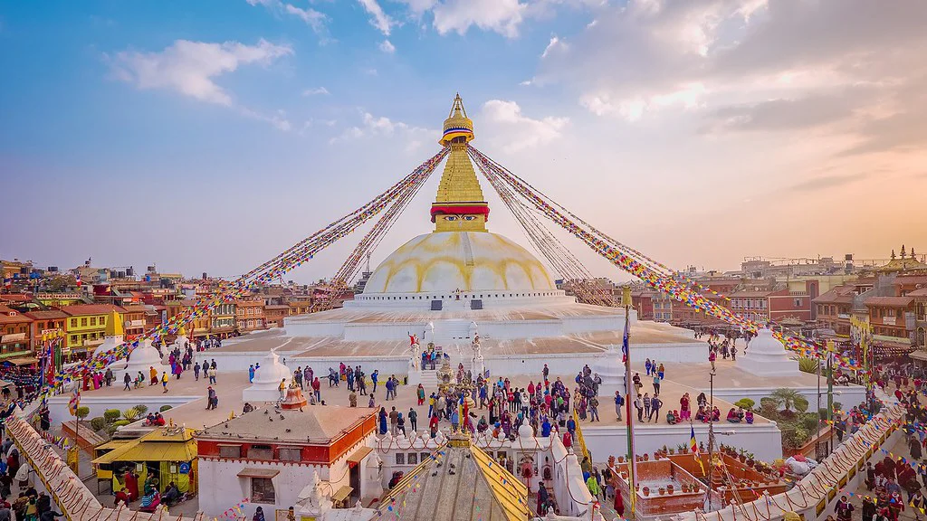 Boudhanath Stupa in Kathmandu during the Best Time for a Luxury Nepal Tour, surrounded by colorful prayer flags and vibrant cultural activity.